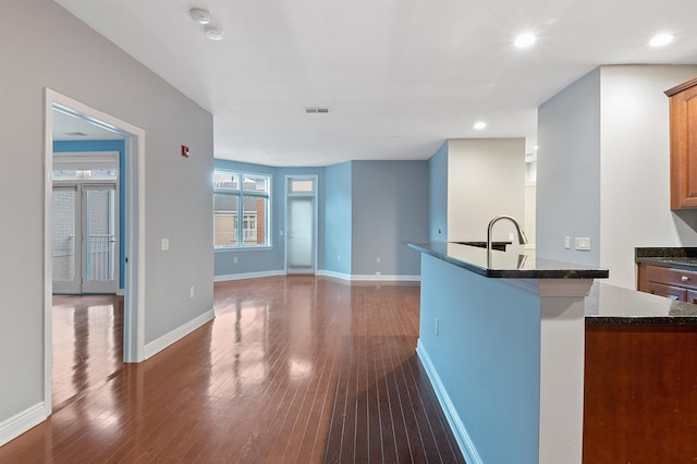 kitchen with sink, dark hardwood / wood-style flooring, and dark stone countertops