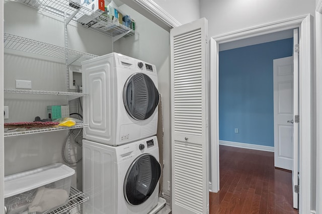 laundry area with dark hardwood / wood-style flooring and stacked washing maching and dryer