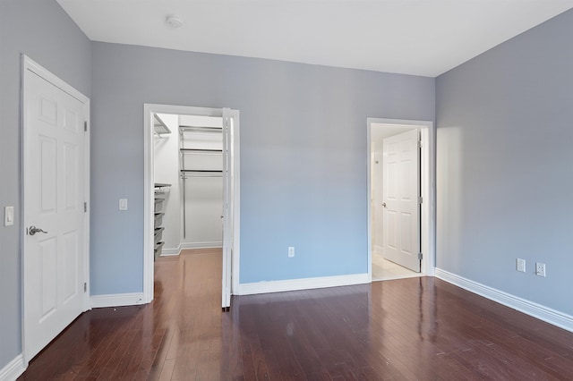 unfurnished bedroom featuring wood-type flooring, a closet, and a spacious closet