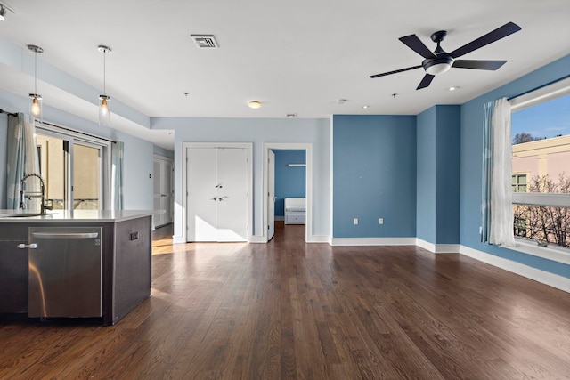 kitchen with a sink, visible vents, light countertops, stainless steel dishwasher, and dark wood-style floors