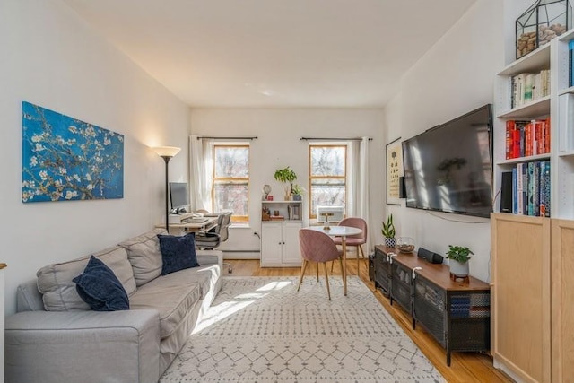 living area with a baseboard heating unit and light wood-style flooring