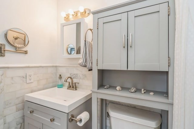 bathroom with vanity, tile walls, toilet, and a wainscoted wall