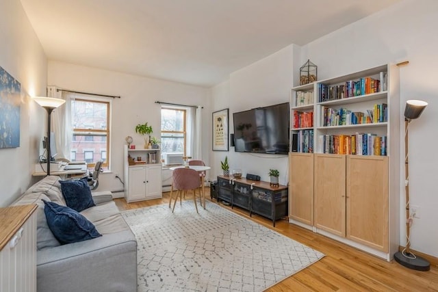 living room with a baseboard heating unit and light wood-style floors