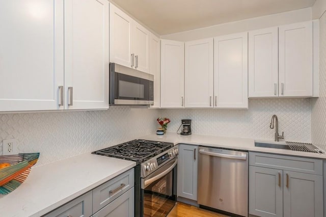 kitchen with a sink, light countertops, gray cabinets, and stainless steel appliances