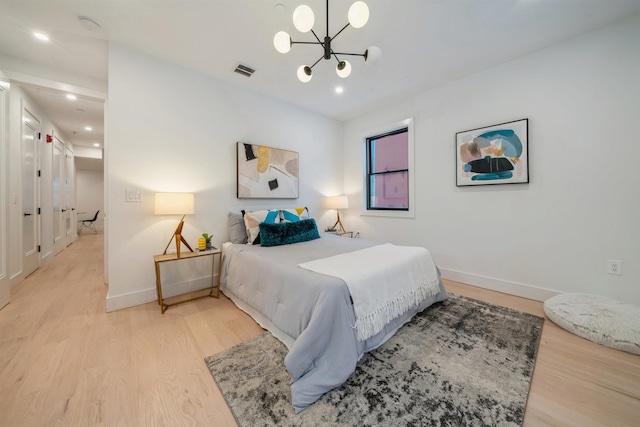 bedroom with light wood-type flooring and an inviting chandelier