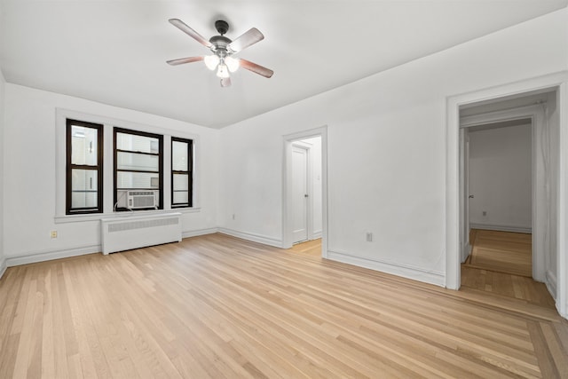 spare room featuring cooling unit, radiator, ceiling fan, and light wood-type flooring