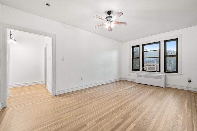 empty room featuring cooling unit, ceiling fan, radiator heating unit, and light hardwood / wood-style floors