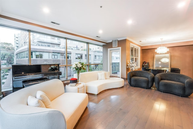 living room with crown molding, wood-type flooring, and a notable chandelier