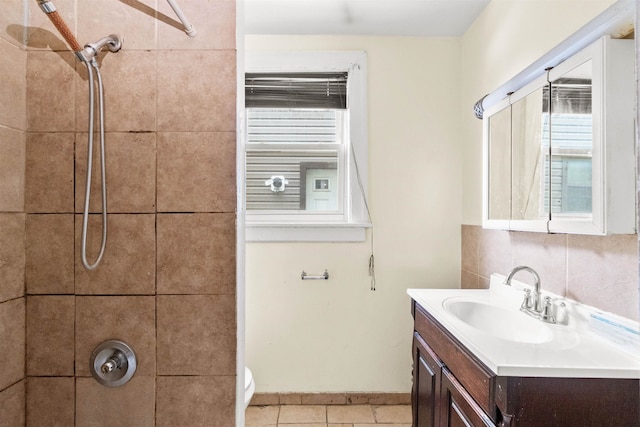 bathroom featuring tile patterned flooring, vanity, toilet, and a tile shower