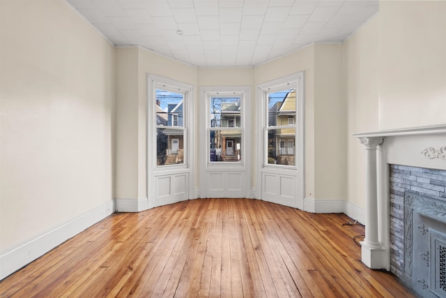 unfurnished living room with a fireplace, light wood-type flooring, and ornamental molding