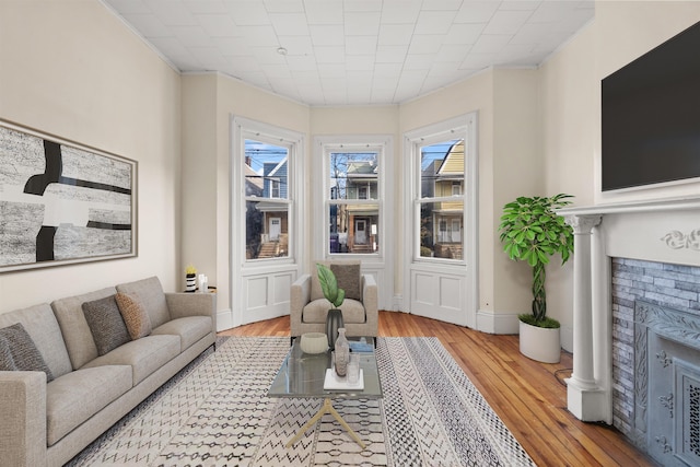 living area with crown molding, light hardwood / wood-style floors, and a fireplace