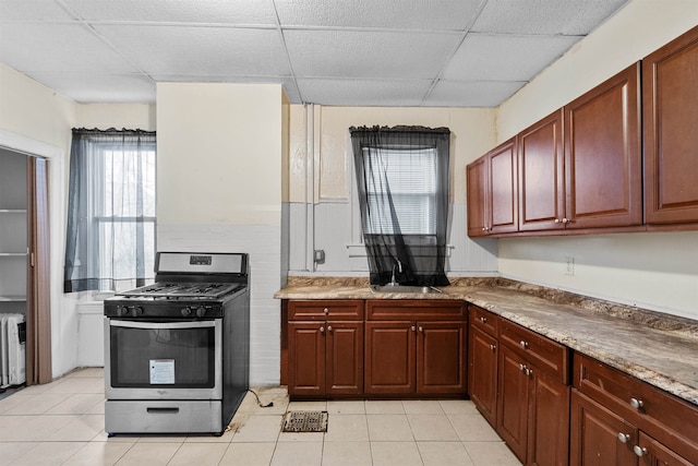 kitchen with plenty of natural light, light tile patterned floors, gas range, and a drop ceiling