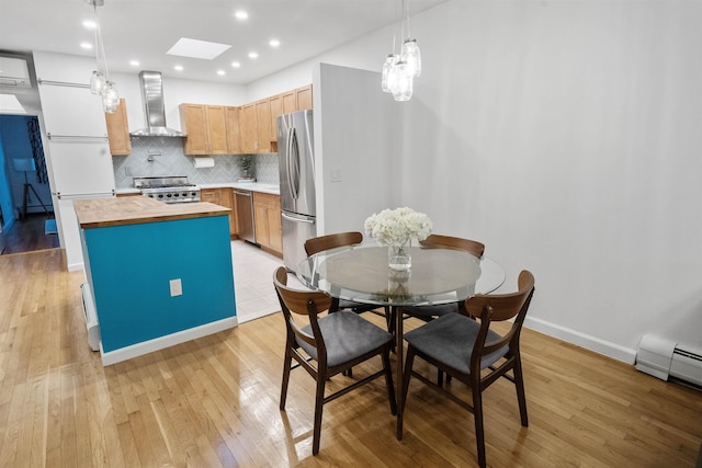 kitchen featuring stainless steel appliances, a kitchen island, wooden counters, wall chimney range hood, and backsplash