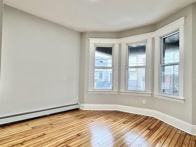 empty room with light hardwood / wood-style floors and a baseboard radiator