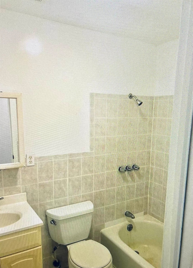 bathroom featuring toilet, vanity, and tile walls