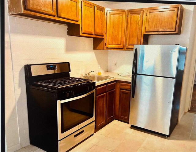 kitchen with stainless steel appliances, sink, and light tile patterned flooring