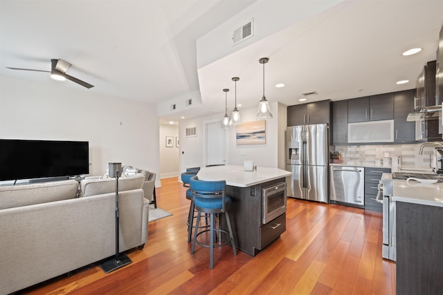 84 Willow Ave Unit 4B, Hoboken, NJ 07030 - kitchen featuring appliances with stainless steel finishes, light countertops, light wood-type flooring, a kitchen breakfast bar, and decorative backsplash