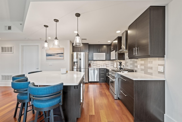 84 Willow Ave Unit 4B, Hoboken, NJ 07030 - kitchen featuring appliances with stainless steel finishes, wall chimney exhaust hood, light countertops, a kitchen bar, and recessed lighting