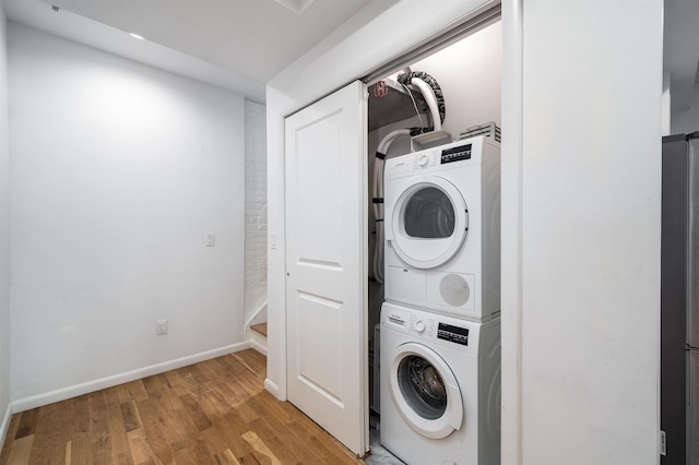 clothes washing area featuring stacked washer / drying machine and light wood-type flooring