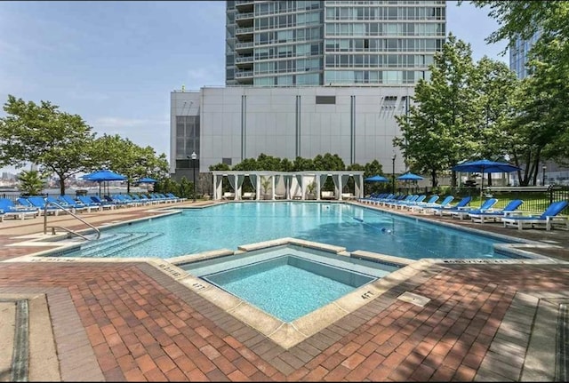 view of swimming pool featuring a pool with connected hot tub and a patio