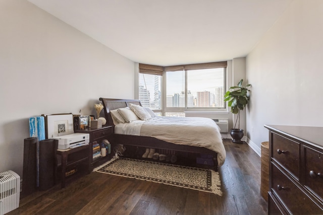 bedroom featuring dark wood-style floors, baseboards, and a view of city