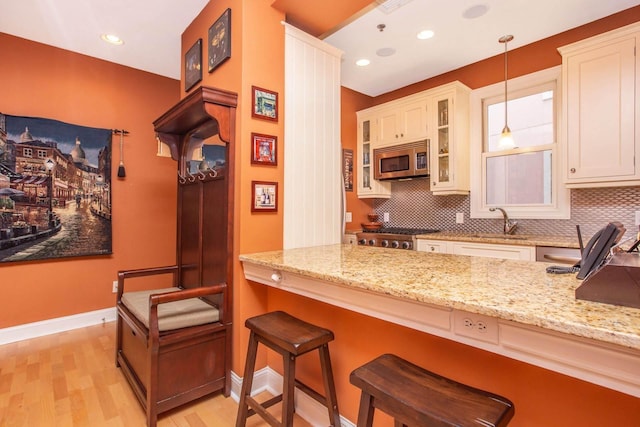 123 Tidewater St Unit B, Jersey City, NJ 07302 - kitchen with stainless steel microwave, decorative backsplash, glass insert cabinets, light stone countertops, and decorative light fixtures