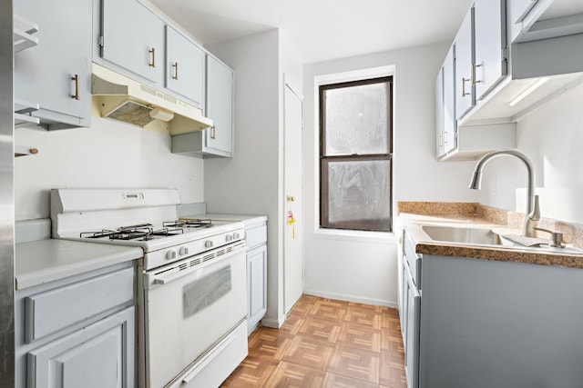 kitchen with light countertops, white range with gas stovetop, a sink, and under cabinet range hood