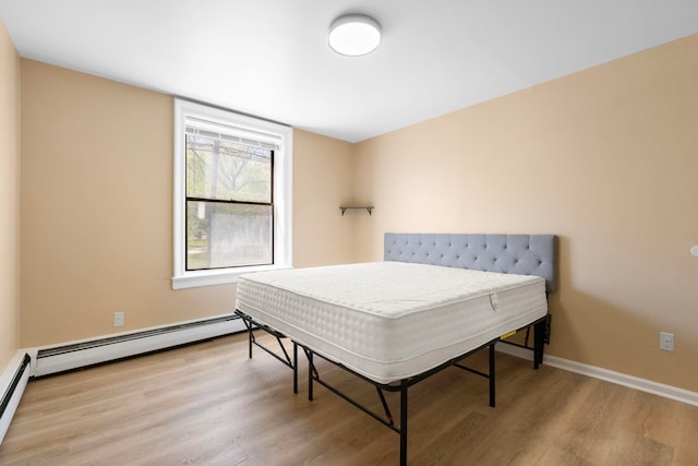 bedroom with baseboards, a baseboard radiator, and wood finished floors