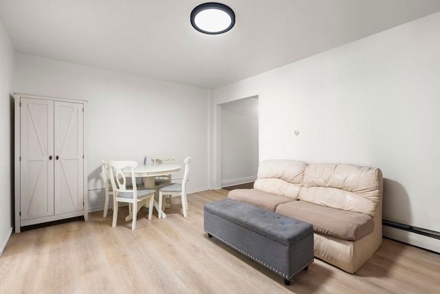 living area featuring light wood-type flooring, baseboards, and a baseboard radiator