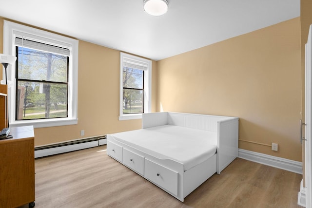 bedroom featuring light wood-type flooring, baseboards, and baseboard heating
