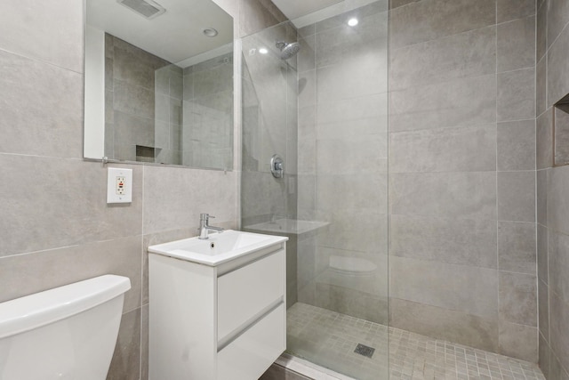 full bathroom with tile walls, a walk in shower, toilet, and vanity