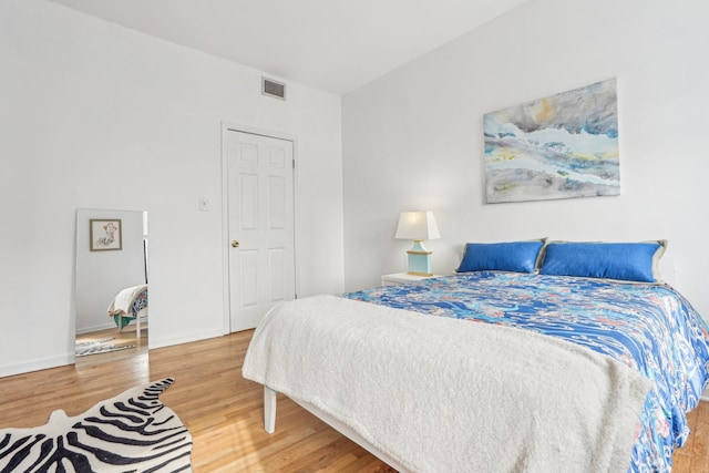 bedroom featuring visible vents, baseboards, and wood finished floors