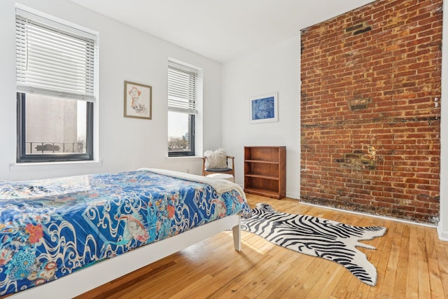 bedroom featuring hardwood / wood-style floors and brick wall