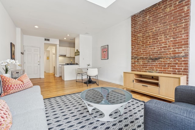 living room featuring light wood-type flooring, visible vents, baseboards, and recessed lighting