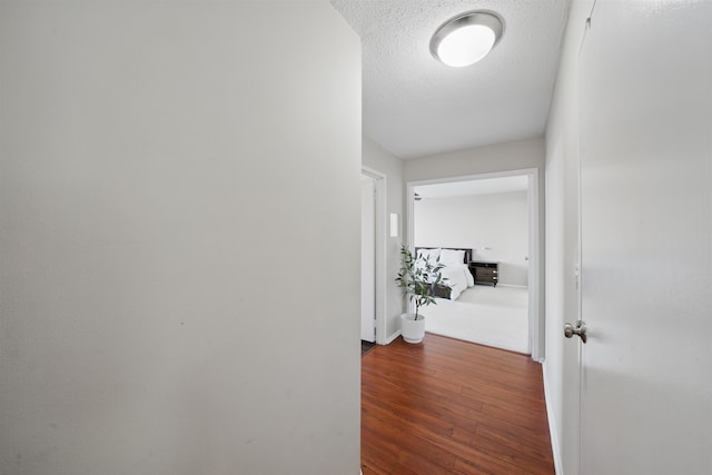 hall featuring a textured ceiling and wood finished floors