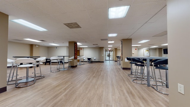 interior space with baseboards, a drop ceiling, and wood finished floors