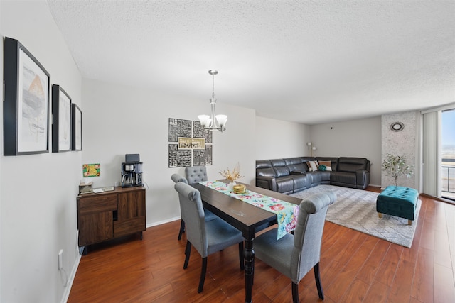 dining space featuring a textured ceiling, hardwood / wood-style floors, baseboards, and an inviting chandelier