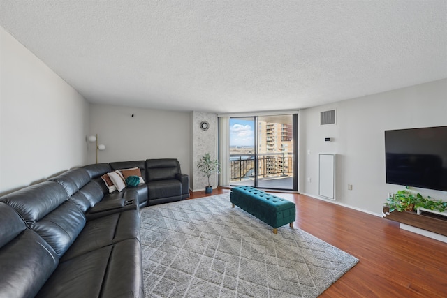 living area featuring baseboards, visible vents, wood finished floors, expansive windows, and a textured ceiling