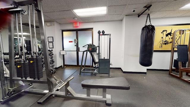 gym with a drop ceiling and baseboards