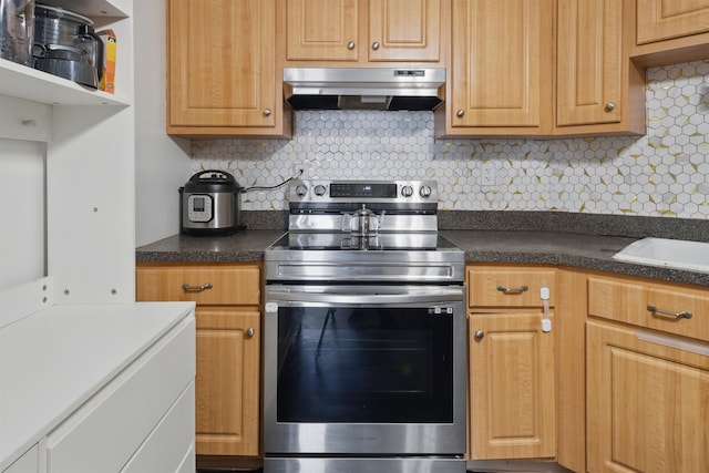 kitchen with dark countertops, backsplash, stainless steel electric range, under cabinet range hood, and a sink