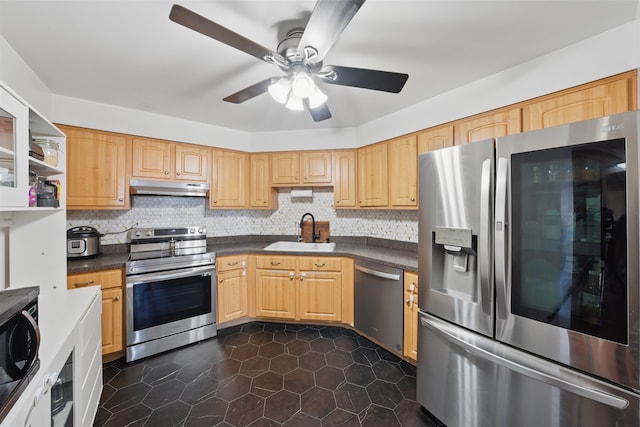 kitchen with tasteful backsplash, dark countertops, stainless steel appliances, under cabinet range hood, and a sink