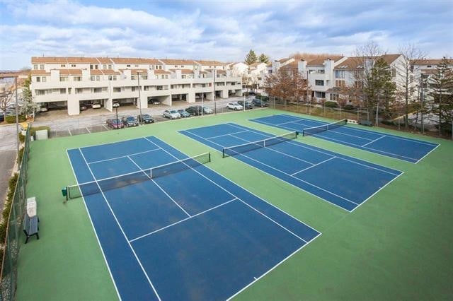 view of tennis court with fence and a residential view