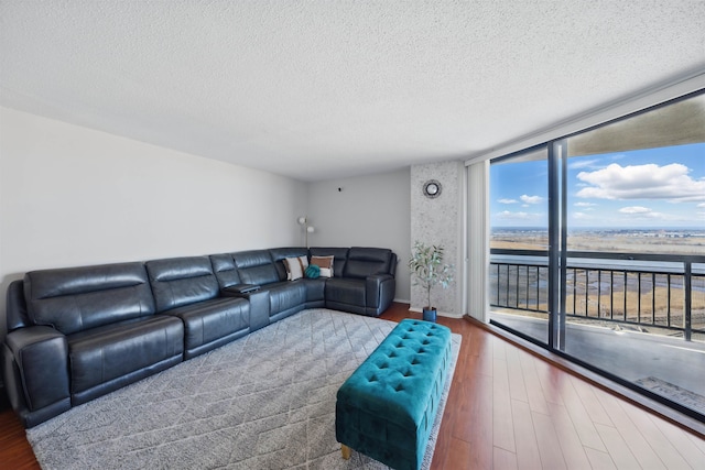 living area with expansive windows, a textured ceiling, and wood finished floors