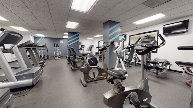 workout area featuring a drop ceiling and baseboards