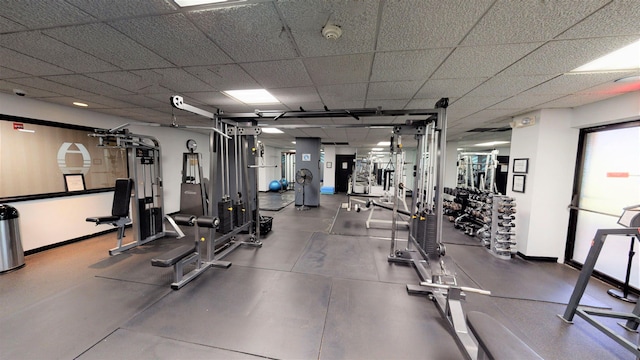 workout area with a paneled ceiling and baseboards