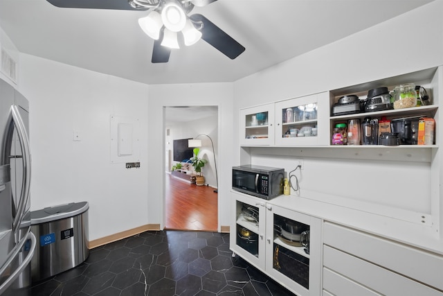 interior space featuring black microwave, dark tile patterned floors, white cabinets, light countertops, and freestanding refrigerator