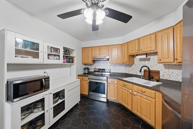 kitchen featuring stainless steel appliances, dark countertops, a sink, and under cabinet range hood