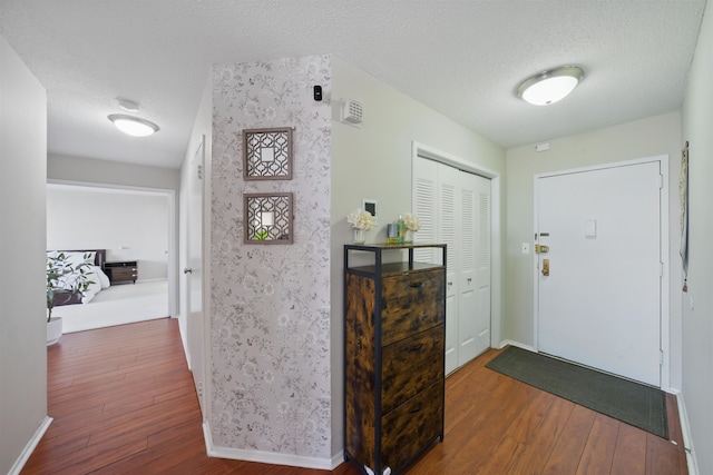 entryway with a textured ceiling, baseboards, and hardwood / wood-style floors