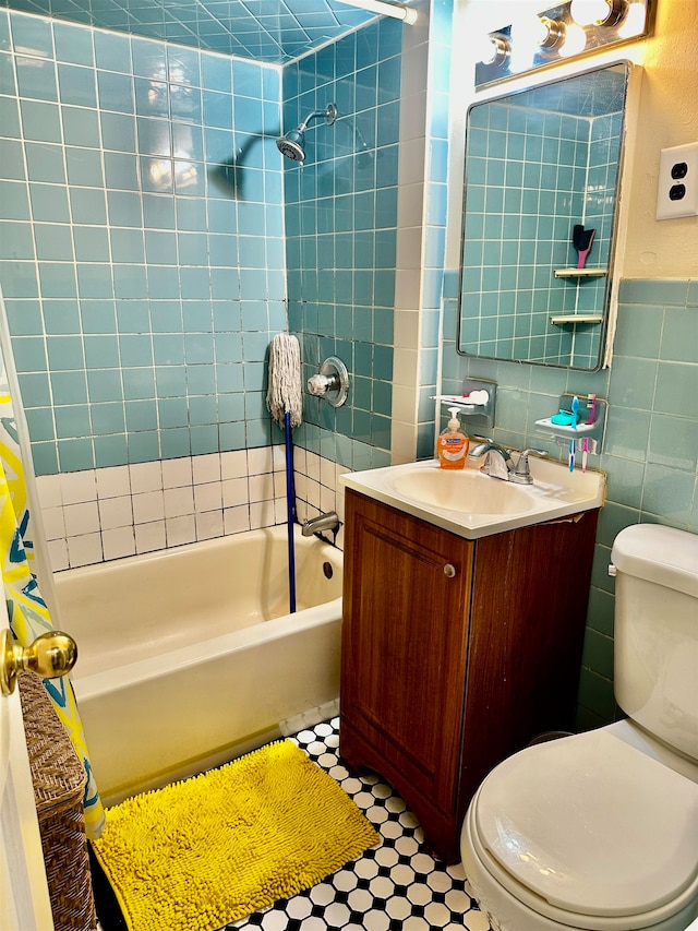 full bathroom with vanity, tiled shower / bath, toilet, and tile walls