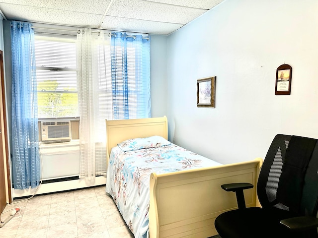 bedroom featuring a drop ceiling, a baseboard radiator, and cooling unit